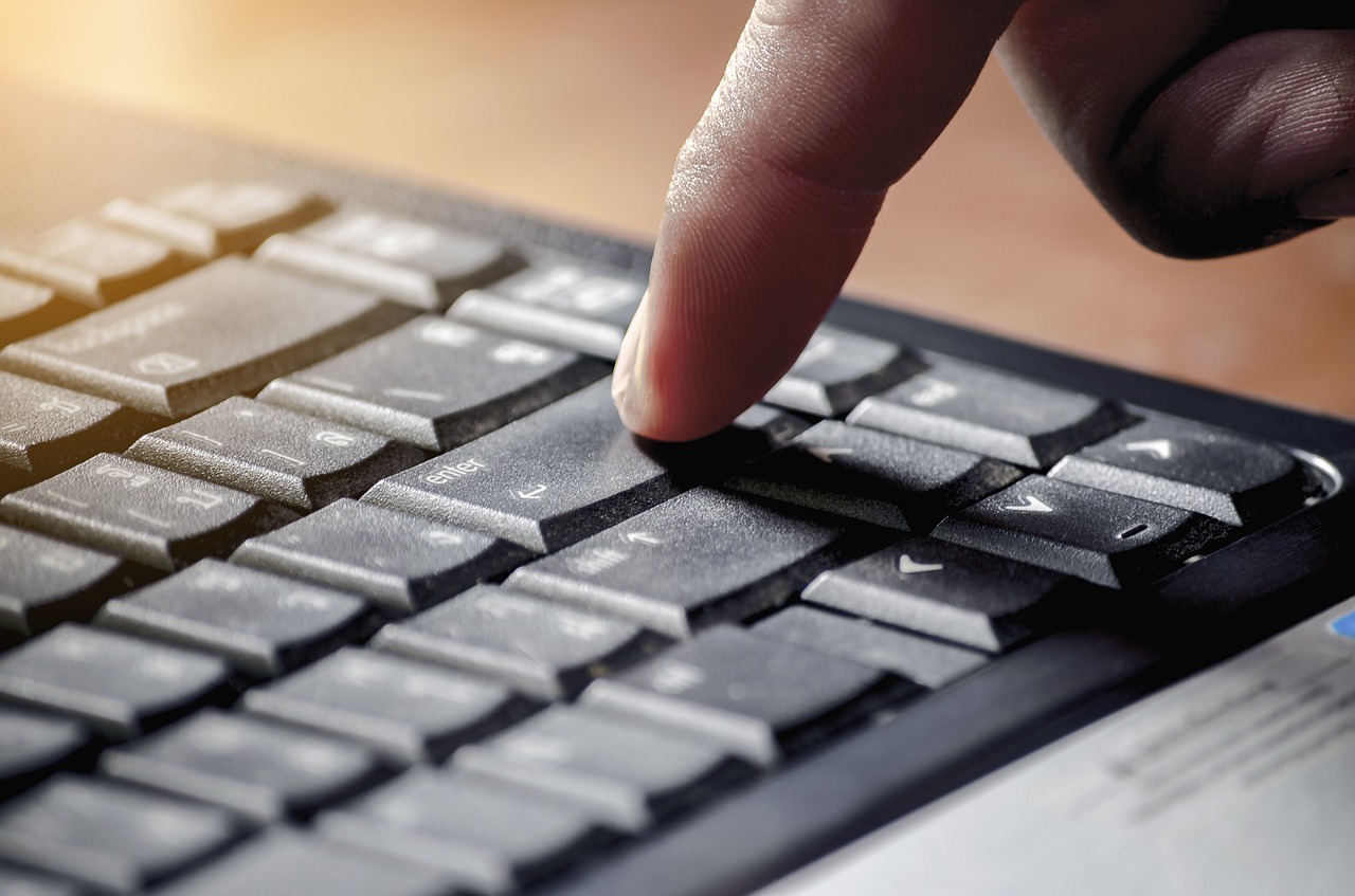 A finger is about to press the enter key on a keyboard