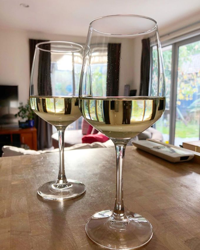 Two wine glasses with champagne in them on a chopping block in a warm, airy, sunny house