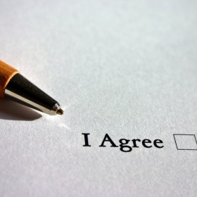 Pen resting on white piece of paper with the words "I Agree" and a check box on it
