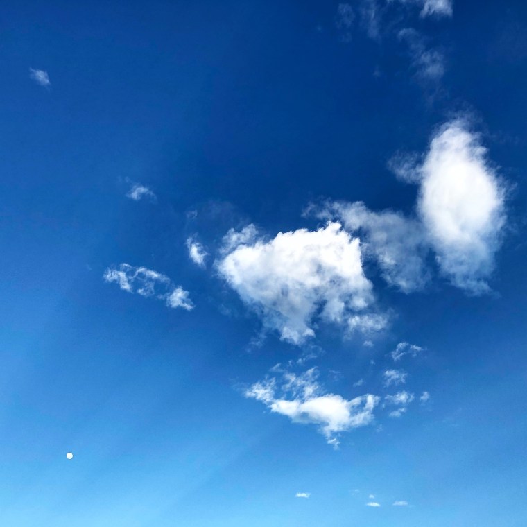 clouds and blue skies with sunshine rays emanating from the corner