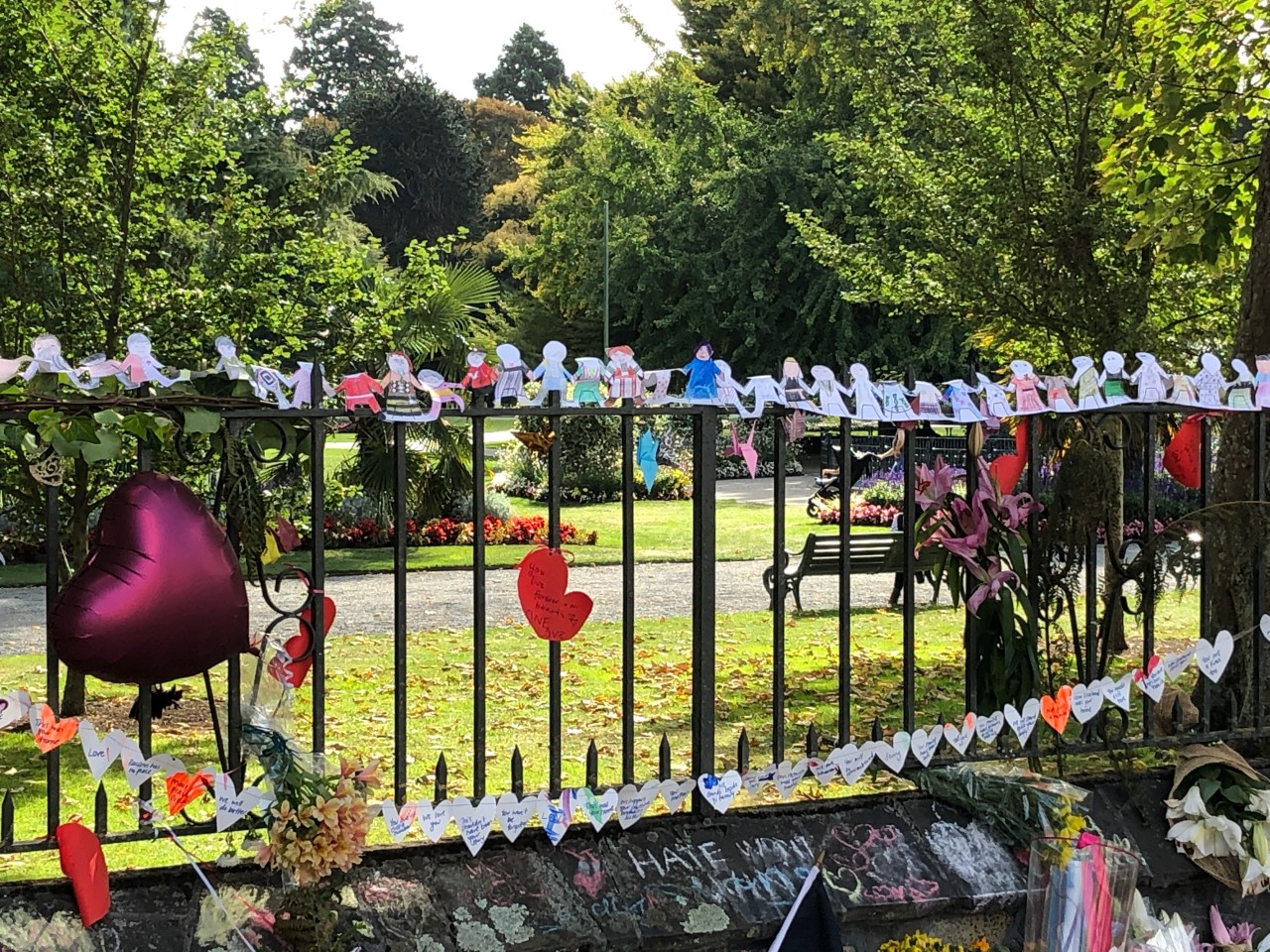 Fence in the Christchurch Botanical Gardens with a chain of paper humans standing holding hands for the victims of the Christchurch terrorist attacks