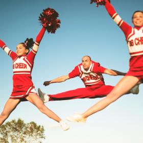 Cheerleaders Wearing Red and White Uniforms, Jumping in the Air