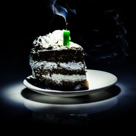 Sad lonely slice of birthday cake with a half-burnt candle on it