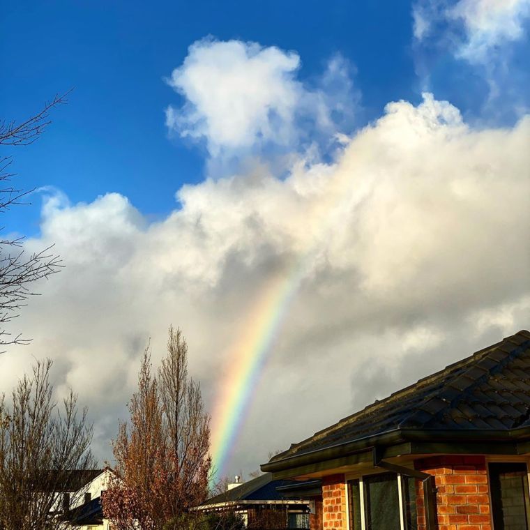 A rainbow bisects the clouds low on the horizon
