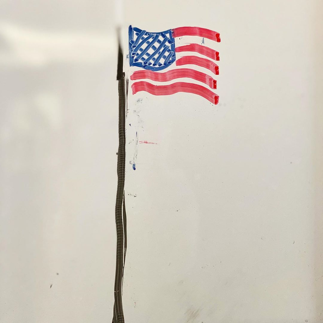 An American flag on a flag pole drawn with whiteboard markers on a whiteboard