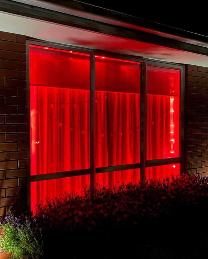 Front window of our house illuminated by red Halloween lights