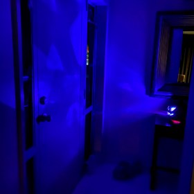 Jack-o'-Lantern glows with a blue light, casting shadows on the door and walls around it