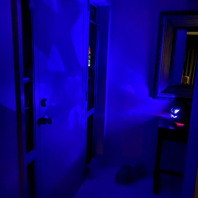 Jack-o'-Lantern glows with a blue light, casting shadows on the door and walls around it