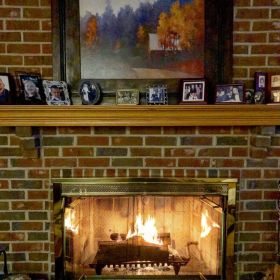 Fireplace with a fire going inside it with family photos on the mantlepiece