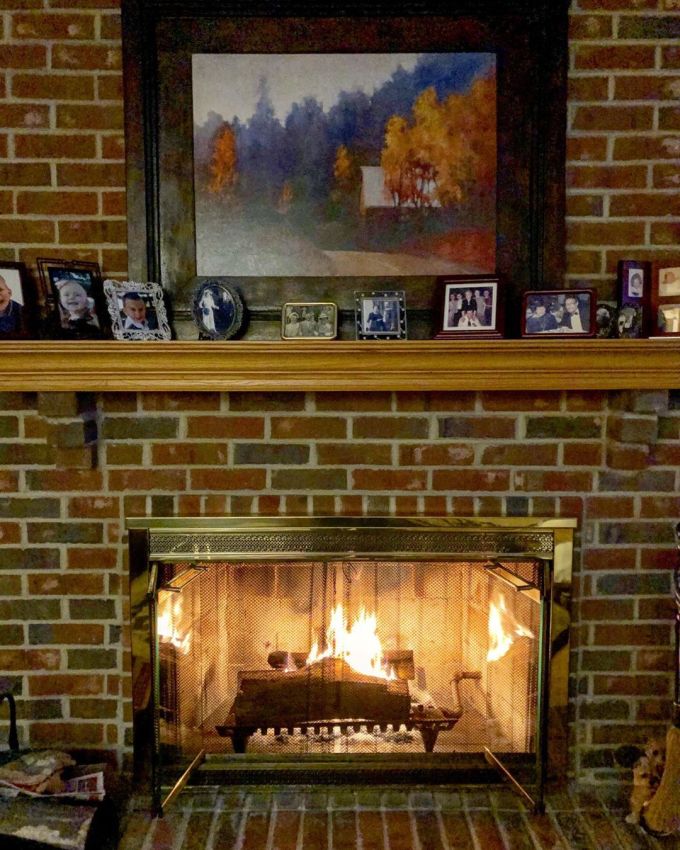 Fireplace with a fire going inside it with family photos on the mantlepiece