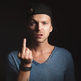 Man in a baseball cap with one eyebrow arched and the middle finger extended