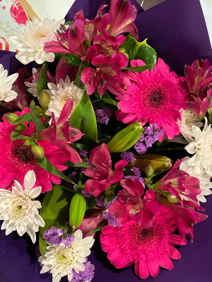 Bouquet of beautiful pink, purple and white flowers surrounded by purple paper