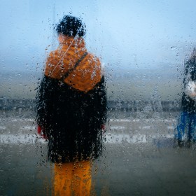 People stand blurred behind a condensation-laden window