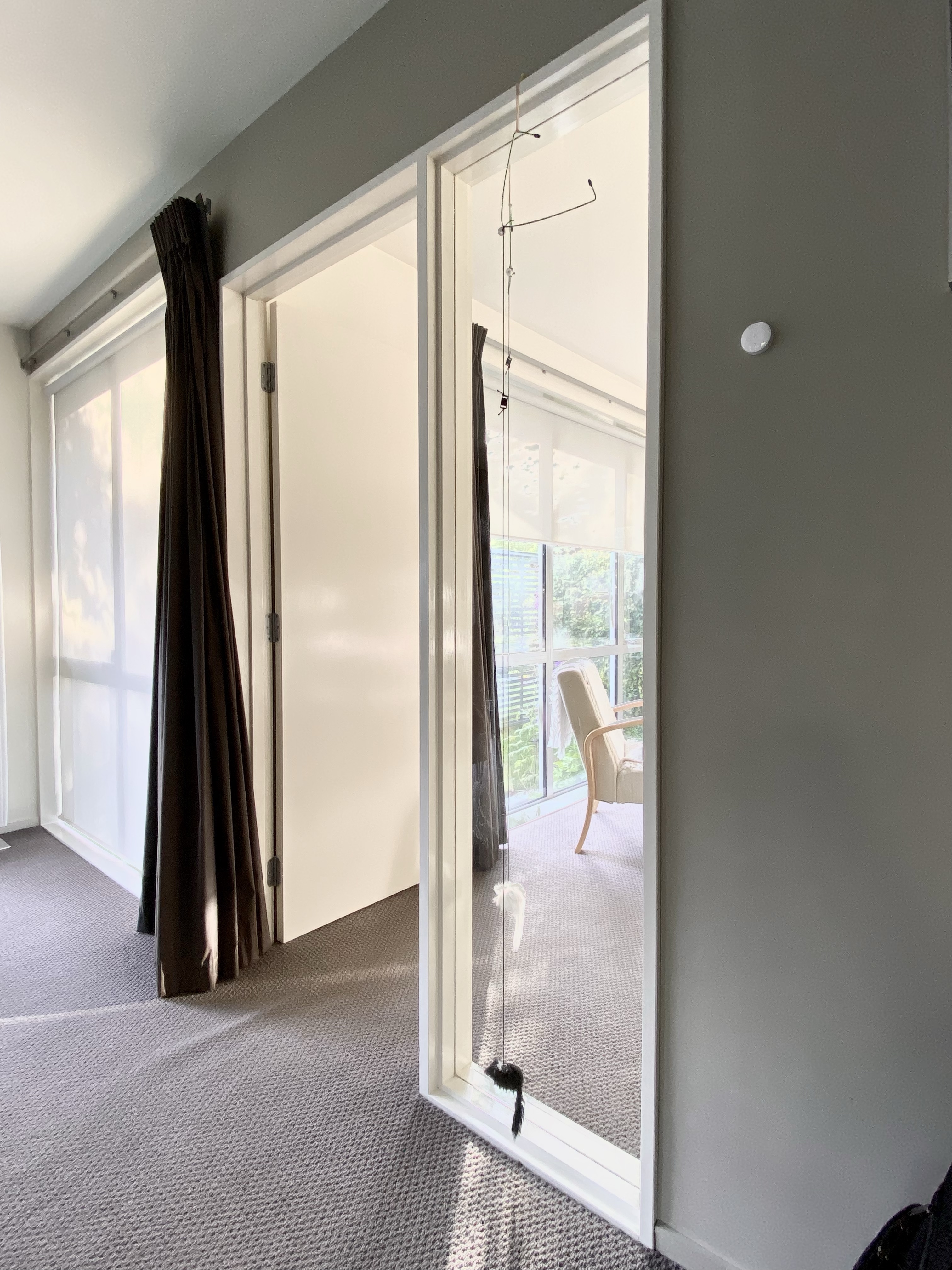 Open door with morning sun shining in; an empty chair sits in the next room.